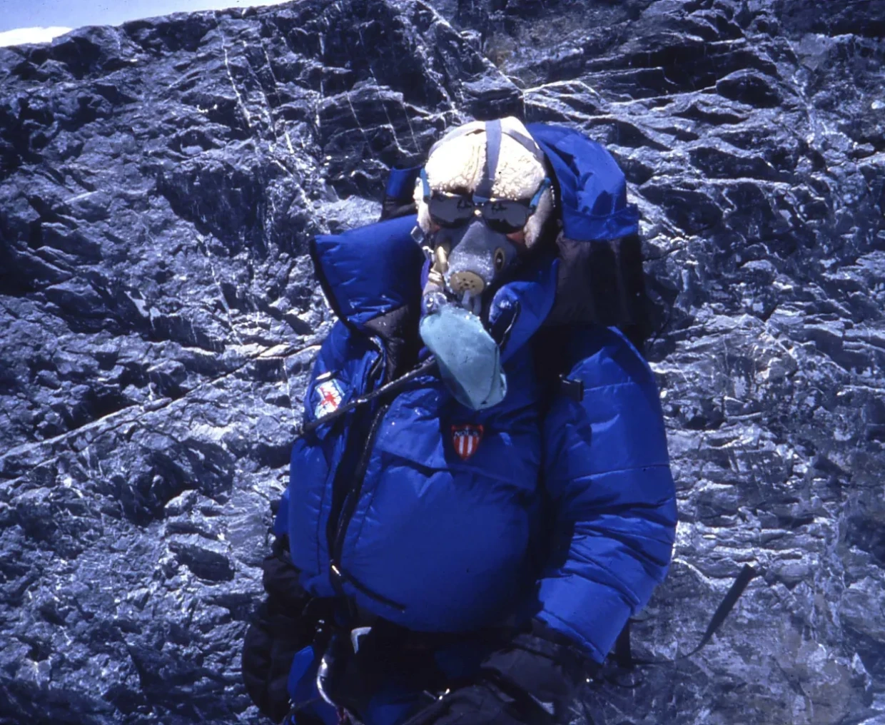 Mountaineer in blue gear on rocky terrain