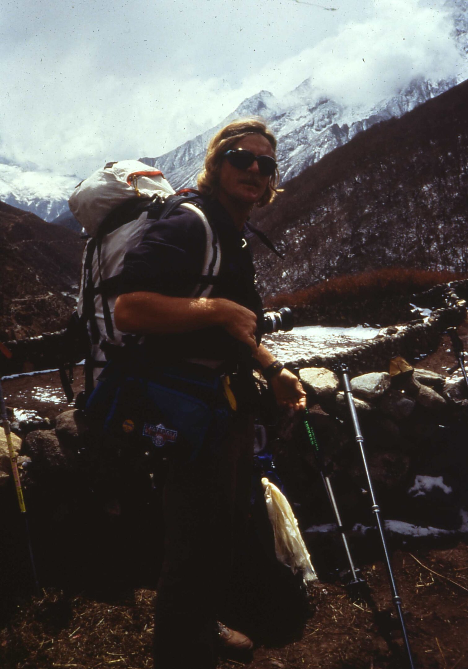 A person hiking in snowy mountainous terrain with trekking poles.