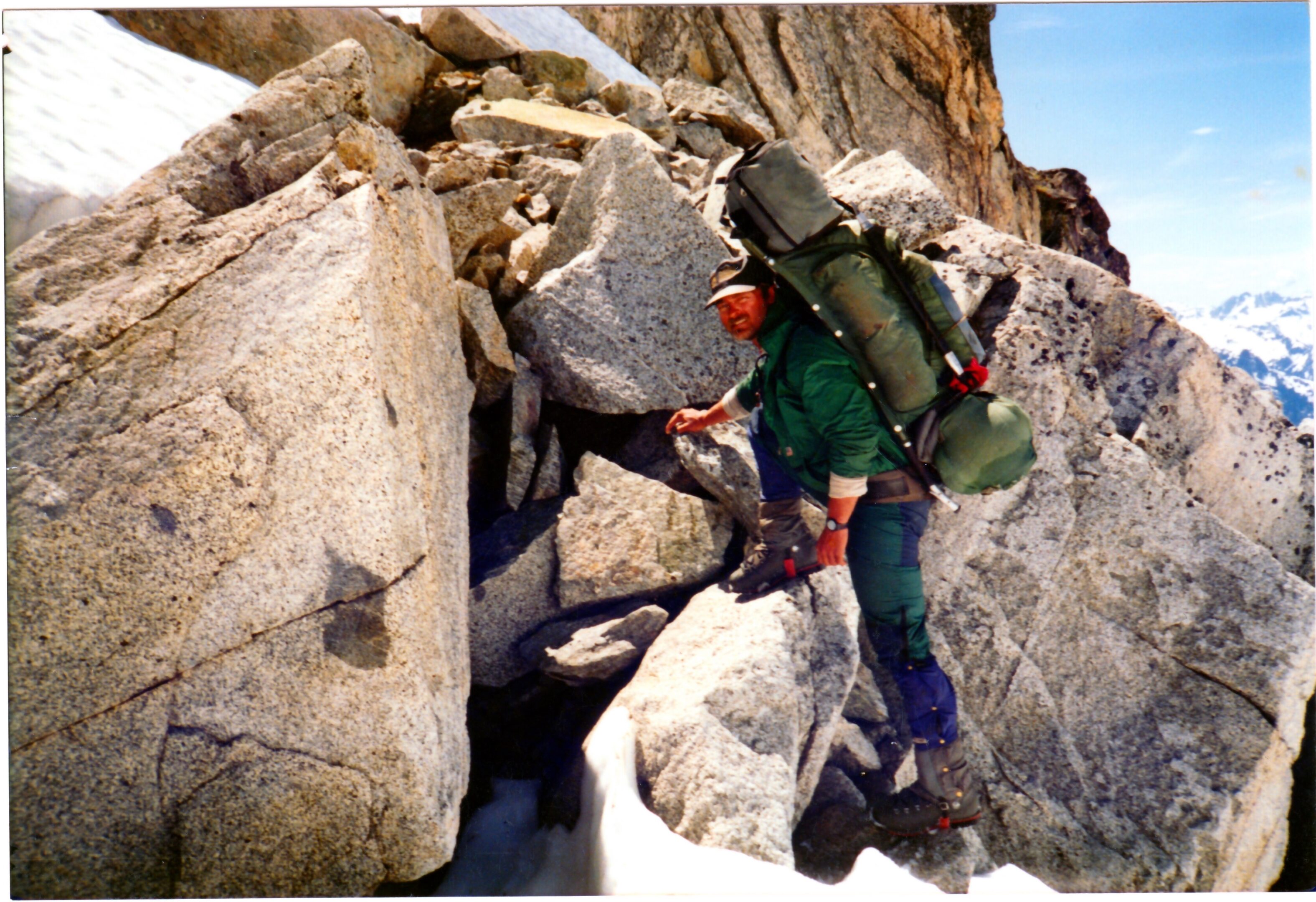 A climber ascending rocky terrain with a backpack and gear.